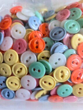 Lot of yellow pink orange blue white green small plastic buttons.